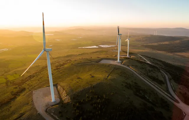 Wind turbines on a hilltop at sunrise, seen from the air