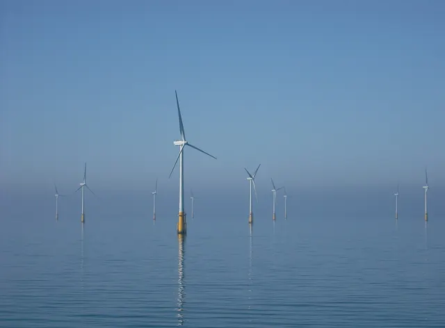 Offshore wind turbines standing in a calm blue sea