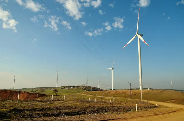 A wind turbine on a grassy rise under a blue sky