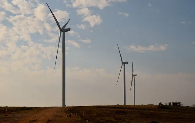 Wind turbines against a cloudy sky over farmland