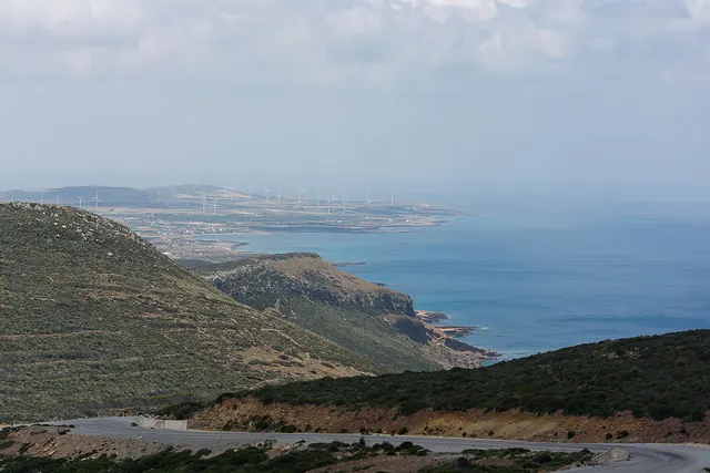A coastal ridge with wind turbines on the plain below