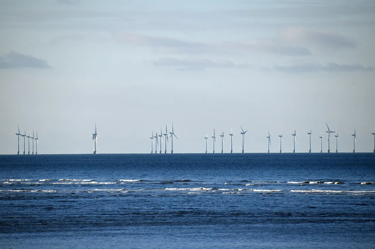 A line of offshore wind turbines beyond rolling waves