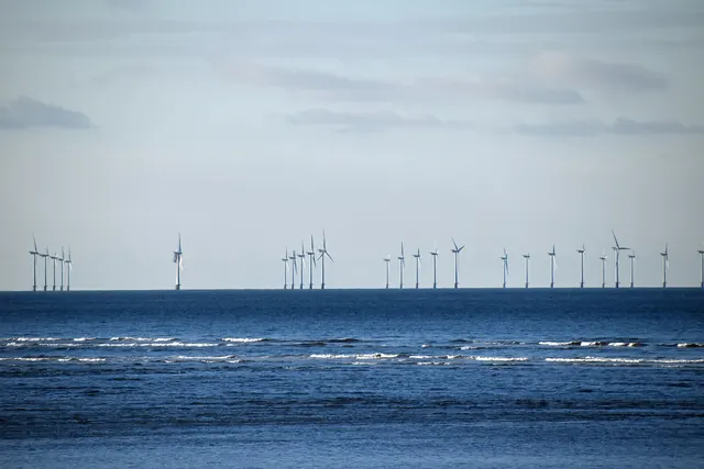A line of offshore wind turbines beyond rolling waves