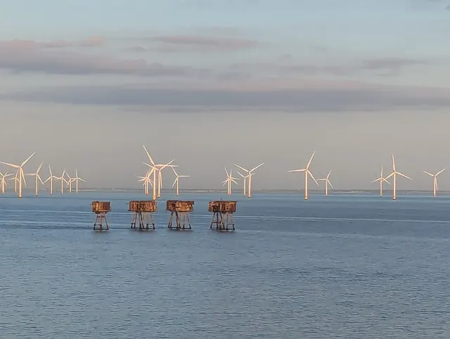 Offshore wind turbines in a pale sea at dusk
