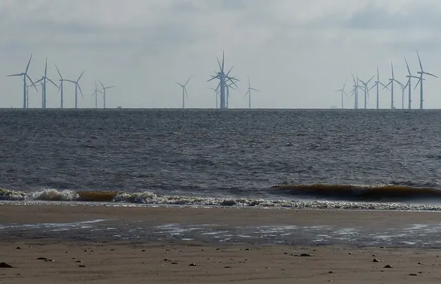 Offshore wind turbines seen from a beach at low tide