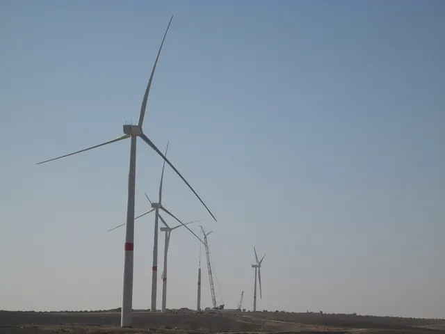 Tall wind turbines rising from flat desert under a hazy sky