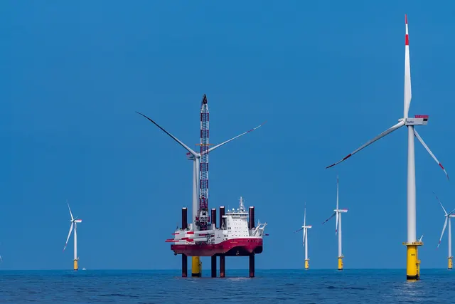 A jack-up vessel beside offshore turbines in a blue sea