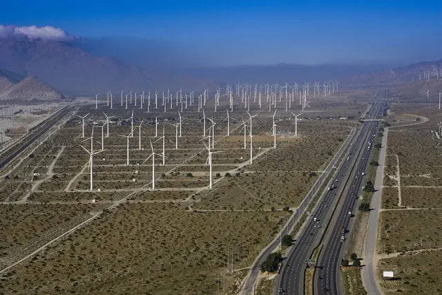 An aerial view of wind turbines along a desert highway