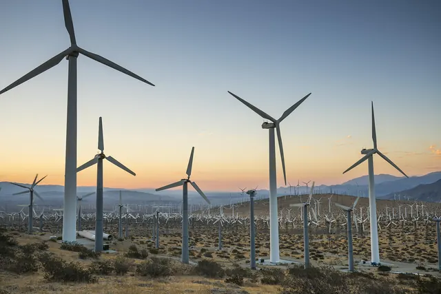 Wind turbines in a desert valley at sunset