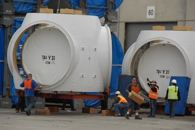 Workers beside turbine nacelles unloaded at a port