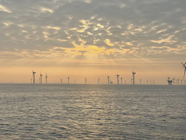 An offshore wind farm under a dappled sunrise sky
