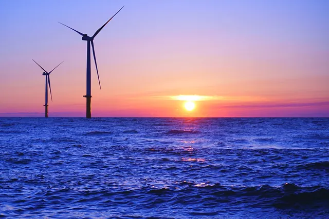 Offshore wind turbines in silhouette against a sunset