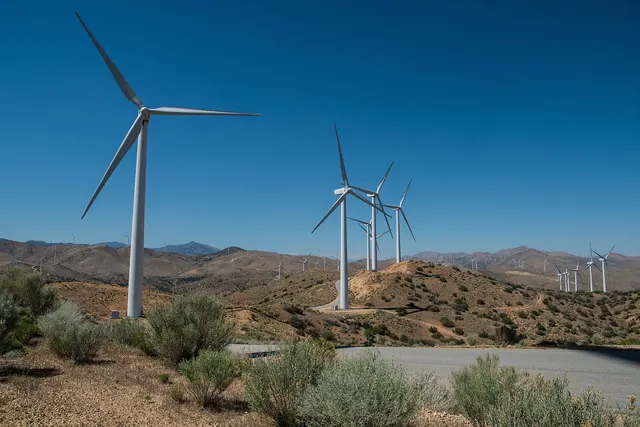 Wind turbines on dry hills under a deep blue sky