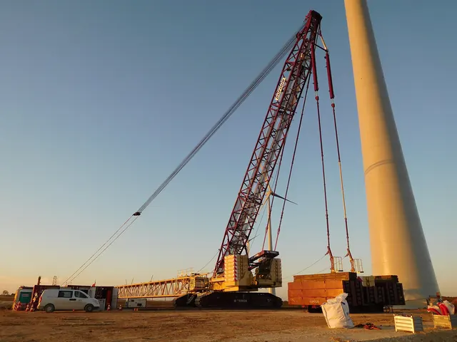 A crawler crane beside a turbine tower at dawn