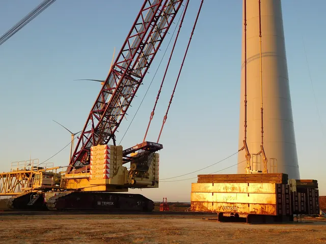 Crane counterweights beside a turbine tower in low sun