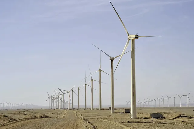 A long avenue of wind turbines along a desert track