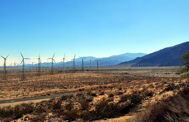 Wind turbines across a desert pass below mountains