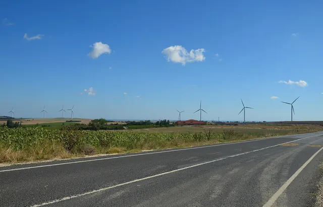 Wind turbines on a low ridge beyond a highway
