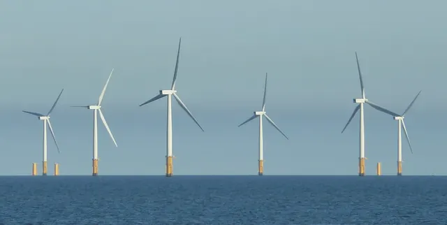 Six offshore wind turbines on yellow foundations