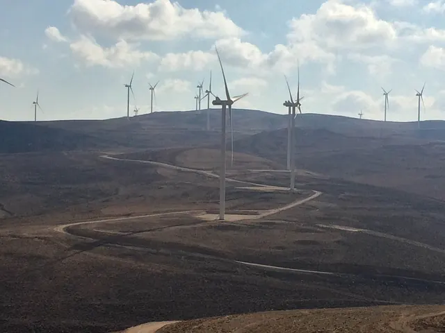 Turbines on rolling brown hills under a blue sky at Tafila