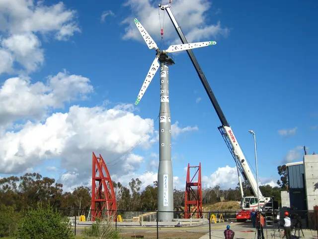 A wind turbine raised by a mobile crane under a bright sky