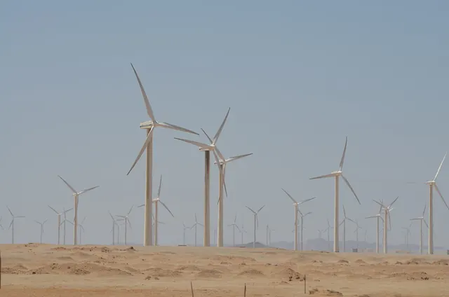 Rows of wind turbines across a flat sand plain