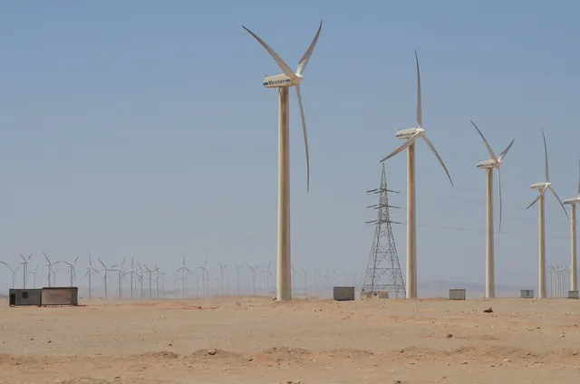 Wind turbines and a power line pylon on open desert