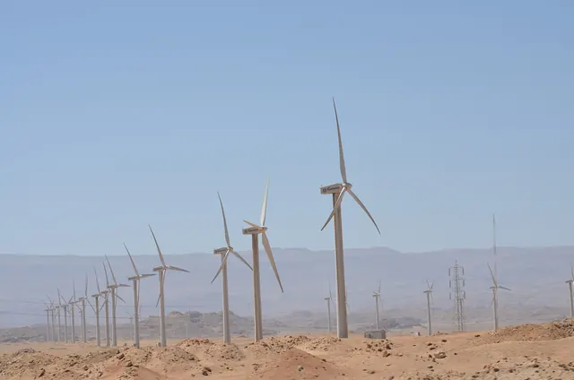 Long lines of wind turbines stretching toward desert mountains