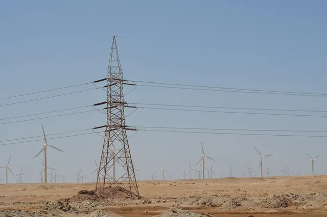 A transmission pylon among wind turbines in the desert