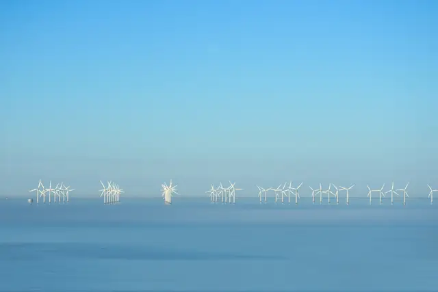 An offshore wind farm on a flat blue horizon